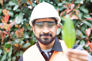 young technician safety glasses and helmet holding a leaf