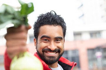 young man with red jacket holding cabbage in the hand