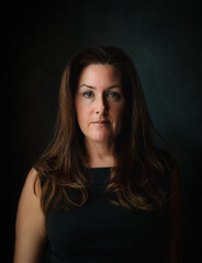Fototapeta premium Close up portrait of attractive woman against dark wall.