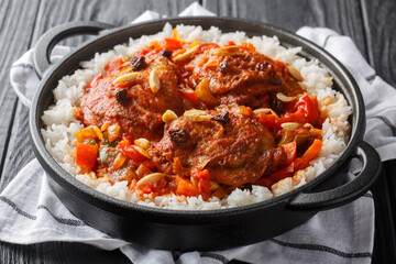 Southern American Country Captain chicken fried and stewed with vegetables, tomato sauce and curry, served with close-up rice in a frying pan on the table. Horizontal