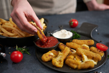 Woman dips Cheese fried mozzarella stick into dip sauce