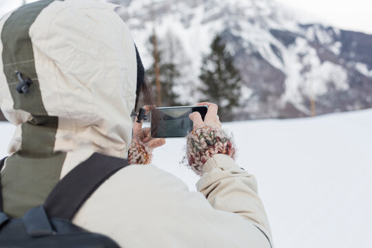 woman in the snow takes a picture with the phone