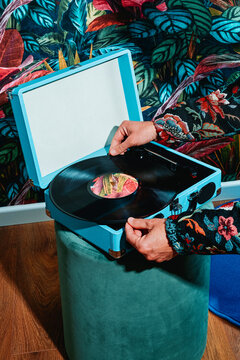 Fototapeta man puts a record in a retro blue turntable