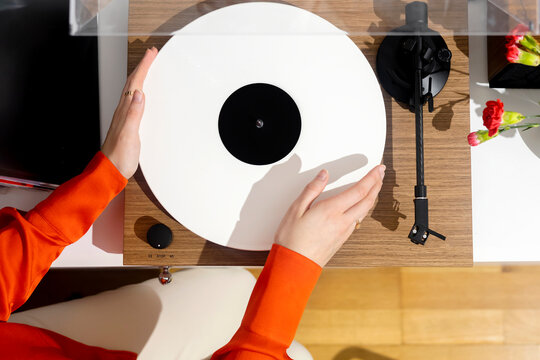 Hands install a vinyl record on a record player to listen to m