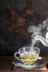 Cup of hot Flowering tea dry tea leaves ,Hot tea in glass cup with steam .hot food and healthy meal concept