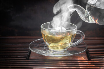 Cup of hot Flowering tea dry tea leaves ,Hot tea in glass cup with steam .hot food and healthy meal concept