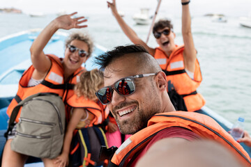 family in tourist boat with life jacket looking at camera happy