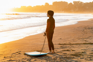 Teenager with surfboard looking at the sea 