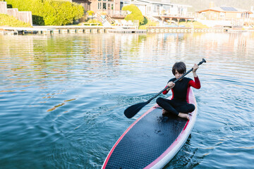 Teen boy on paddleboard by the summerhouse lake