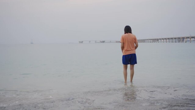 Young Asian woman in walking and playing on tropical beach at summer sunset. Happy female enjoy and fun outdoor activity lifestyle on holiday travel vacation at the sea
