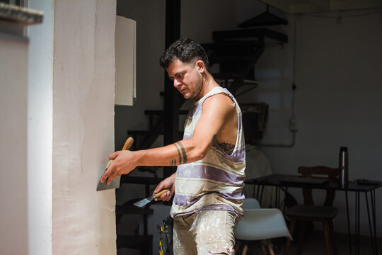 Trans man repairing a wall 