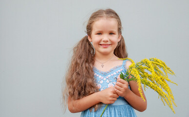 Portrait of a happy girl with long hair on a blue background. The child smiles happily.
