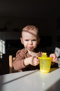 Toddler Makes Funny Face While Drinking Milk from Sippy Cup