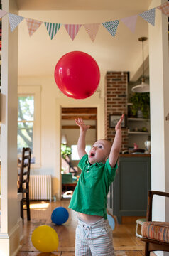 Boy Plays with Red Balloon at his 2nd Birthday Party
