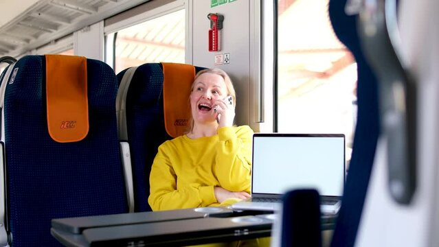 woman in train InterCity advertises new product on laptop She is talking on the phone calling smiling showing finger on chroma key advertising space Delight joy lovely and showing thumb up