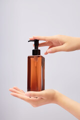 Female hand model holding a transparent pump bottle on white background. Empty label for product mockup. The concept of beauty care products