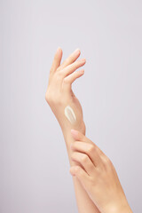 Beautiful woman's hand applying cream on back of hand, applying lotion on skin. Close-up in light background. Skin care concept, try anti-irritant cream