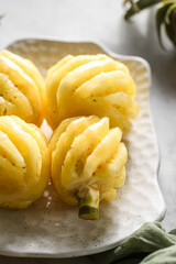peeled small pineapple on a white plate