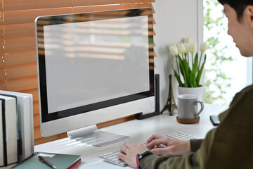 Side view of focused man freelancer looking at computer monitor, working online at home.