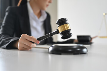 Close up view of Judge hand holding gavel and hitting sound block. Lawyer, attorney and justice concept.