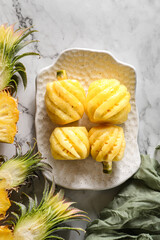 peeled small pineapple on a white plate