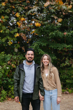 Portrait of a couple standing together outside near trees.