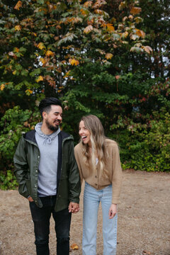 Fun couple standing together outside near trees.