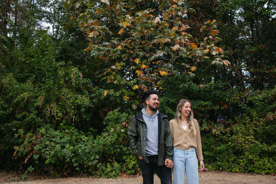Fun couple standing together outside near trees.