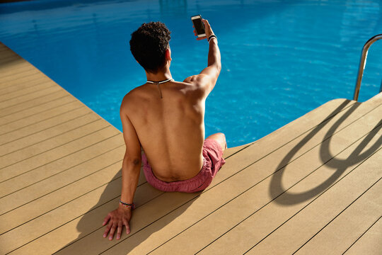 Young man taking selfie near pool