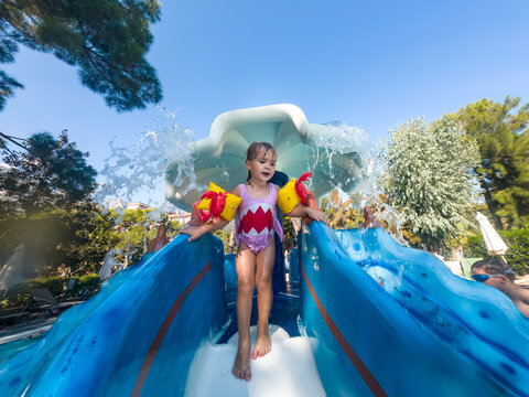 cute girl enjoying water slide during family vacation