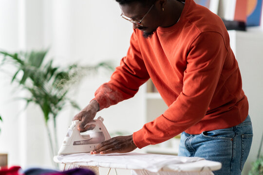 Crop man ironing clothes