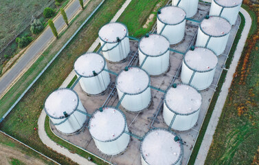 Aerial view of a group of chemical production tanks located in a fenced industrial area. Bird's eye view of the chemical terminal tanks in the middle of the day. Industrial concept.
