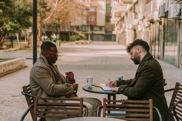 Obraz premium Young executive ceo manager writing notes in the notebook and explaining them to his black male partner