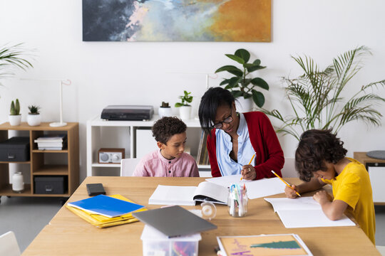 Black mother helping sons with homework
