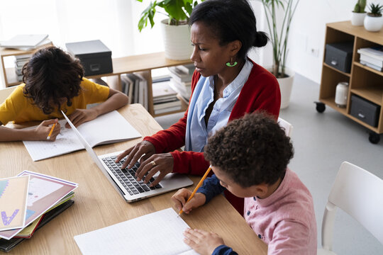 Black woman working remotely sons doing homework