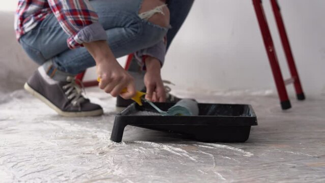 Close-up of builder hands using paint roller in his work indoors. paint roller in tray.