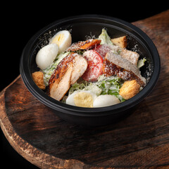 Caesar salad in round black lunchbox