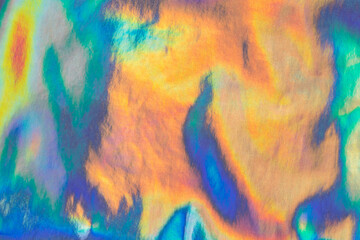 Iridescent rainbow-colored texture with a shining surface. Abstract background