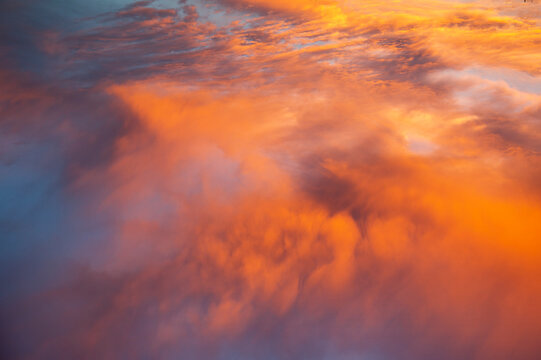 Fototapeta dramatic orange clouds in the blue sky at sunset