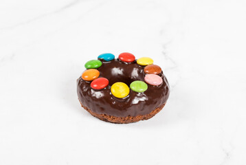 Easter Chocolate donut with chocolate glaze and decorated with colored candy dragees. White background