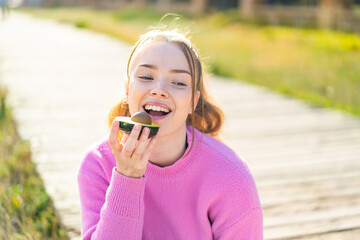 Fototapeta premium Young pretty girl at outdoors holding an avocado