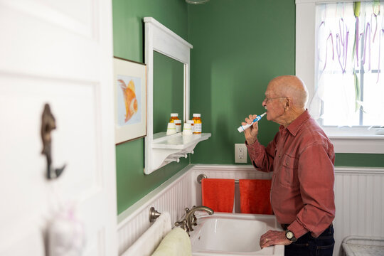 Lone Senior Citizen man brushing teeth at home