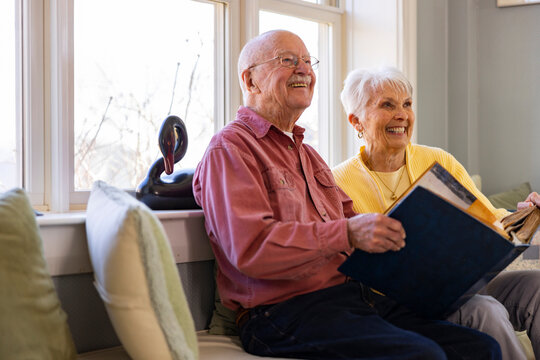 Senior Citizen couple at home Looking at photo album look at friend 