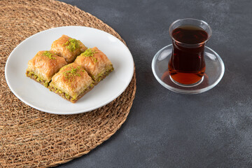 Pistachio baklava on a white plate with Turkish tea.A plate of traditional baklava on black background
