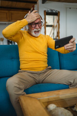 senior old man sit at home play video games on smartphone mobile phone