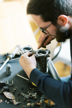Millennial Man assembling carburetor on kitchen table in his home 