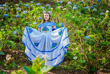 Young Nicaraguan woman in traditional folk costume in a field of Milflores, Smiling woman in...
