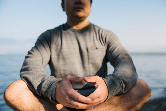 Mindful man meditiating outside on rocks.