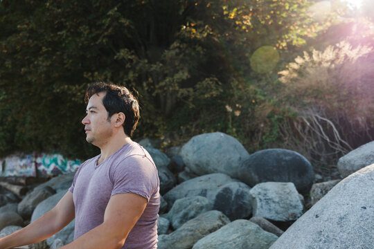 Mindful man meditiating outside on rocks.