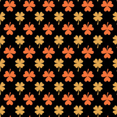 Black seamless pattern with orange and beige clover leaves